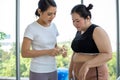 Young female trainer measuring fat layer of overweight woman with caliper at fitness Royalty Free Stock Photo