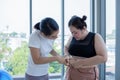 Young female trainer measuring fat layer of overweight woman with caliper at fitness Royalty Free Stock Photo