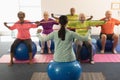 Young female trainer and senior people exercising with resistance band