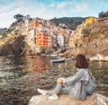 Female traveler with backpack enjoying great view on the famous landmark town Riomaggiore in Italy Royalty Free Stock Photo