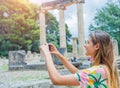 Young female traveler making photo. Famous Archaeological Site of Olympia. Peloponnese, Greece. Travel concept