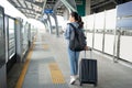 Young female traveler walking with black suitcase at modern transport stop outdoors, back view The concept of urban transport and Royalty Free Stock Photo