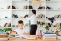 Young female tutor helping little elementary school boy with homework during individual lesson at home