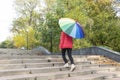 Young female under big colorful umbrella is coming upstairs Royalty Free Stock Photo
