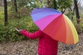 Young female under colorful umbrella checking rain with her hand Royalty Free Stock Photo