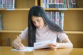 Young female university student concentrate doing language practice examination inside library Royalty Free Stock Photo