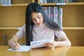 Young female university student concentrate doing language practice examination inside library Royalty Free Stock Photo