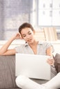 Young female using laptop at home sitting on sofa