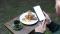 Female using smart phone taking pictures of coffee and cake during resting in cafe. Royalty Free Stock Photo