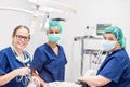 Young female veterinarian doctors posing smiling, inside operating room after successful surgery. Animals healthcare