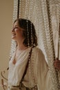 Young female in victorian shirt sitting in giant crystal chandelier and smile