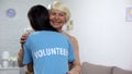 Young female volunteer hugging smiling aged lady, old people care, nursing home Royalty Free Stock Photo