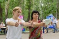 Young female volunteer shows middle-aged woman plus size how to properly hold fat monitor in their hands for proper measurement