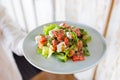 The young female waiter holding in her hands the plate with the Greek salad. Royalty Free Stock Photo