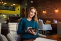 Young female is watching video on digital tablet during rest in modern coffee shop Royalty Free Stock Photo