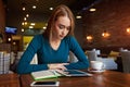 Young female is watching video on digital tablet during rest in modern coffee shop Royalty Free Stock Photo