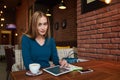 Young female is watching video on digital tablet during rest in modern coffee shop Royalty Free Stock Photo