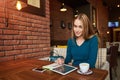 Young female is watching video on digital tablet during rest in modern coffee shop Royalty Free Stock Photo