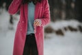 Young female wearing a blue shirt and a pink coat in a winter land covered in snow