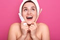 Young female with white towel on head an d nacked shoulders, ready for brushing teeth, looking up with open mouth and happy facial