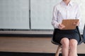 Young female woman in formal wear waiting for interview, sitting on chair in front of office interview room, and holding clipboard Royalty Free Stock Photo