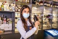 Young female worker at bartender desk in restaurant bar preparing coctail with shaker. Beautiful young woman behind bar wearing Royalty Free Stock Photo