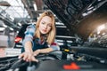 Young female worker stretching her arm to the engine compartmant