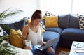 Young female working on tablet computer sat on sofa Royalty Free Stock Photo