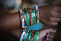 Young female's arm with several multi-colored bracelets adorning her wrist.