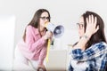Young female yelling through megaphone at her coworker Royalty Free Stock Photo