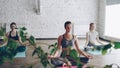 Young female yoga students are meditating in lotus position in the end of practice in beautiful light studio. Relaxation