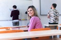 Young femaleeconomy student analyzing company annual financial report balance and prepairing for test. Smoling into camera.