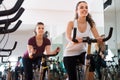 Young females of different age training on exercise bikes Royalty Free Stock Photo