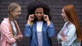 Young females mocking black classmate, bullying victim closing ears, conflict