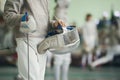 Young fencer holding foil and protective mask in his hand on the fencing tournament