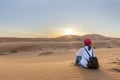 A young fermale traveler enjoys a sunrise or sunset landscape view of the desert sand dunes of Erg Chebbi near the village of Royalty Free Stock Photo