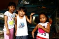 Young Filipino children play on a parked vehicle and smile for the camera