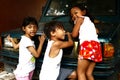 Young Filipino children play on a parked vehicle and smile for the camera