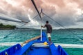 Young filipino man standing at edge of yacht looking at sea. Travelling on old boat at cloudy day.