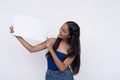 A young Filipino woman smiling while looking at a blank white signage or placard she is holding. Isolated on a white background Royalty Free Stock Photo