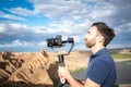 Young filmmaker filming natural landscape in canyon with a large river and marshes