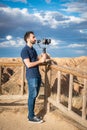 Young filmmaker filming natural landscape in canyon with a large river and marshes