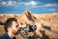 Young filmmaker filming natural landscape in canyon with a large river and marshes