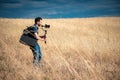 Young filmmaker filming natural landscape in canyon with a large river and marshes