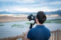 Young filmmaker filming natural landscape in canyon with a large river and marshes