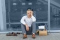 A young fired office worker is sitting under his office.