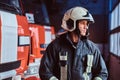 Young fireman wearing protective uniform standing next to a fire engine in a garage of a fire department Royalty Free Stock Photo