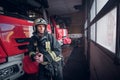 Young fireman wearing protective uniform standing next to a fire engine in a garage of a fire department Royalty Free Stock Photo