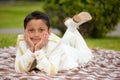 Young First Communion boy lying on a blanket over the grass