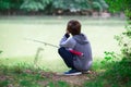 Young fisher. Boy fishing at river bank, summer outdoor. Young boy sitting at river bank with rod and fishing. Summer leisure Royalty Free Stock Photo